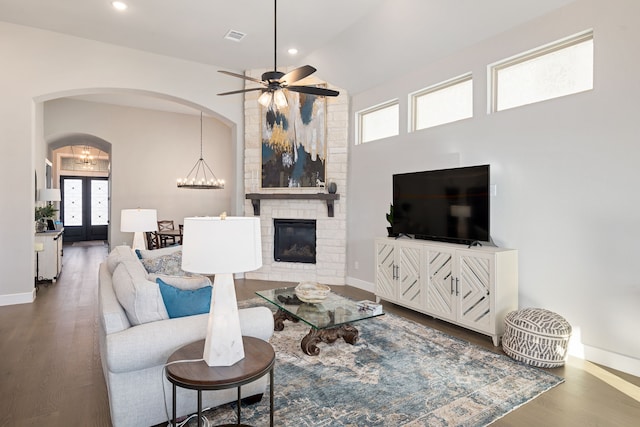 living room featuring french doors, a fireplace, ceiling fan with notable chandelier, and hardwood / wood-style floors