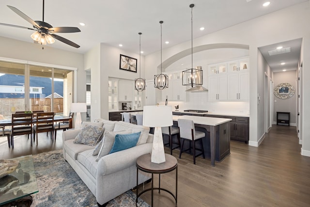 living room with ceiling fan with notable chandelier and dark hardwood / wood-style floors