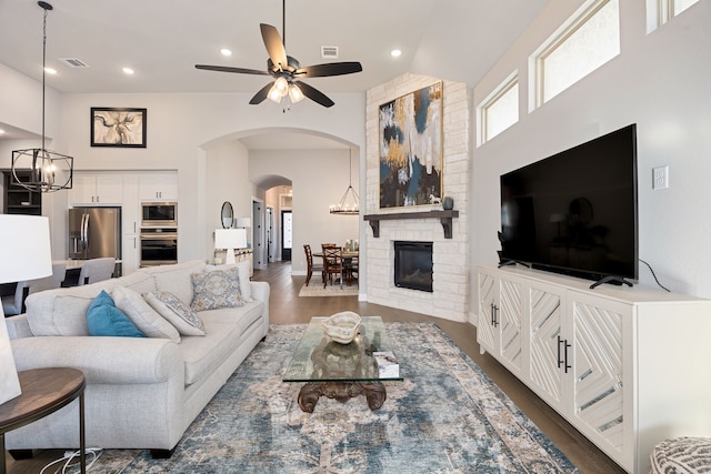 living room featuring dark hardwood / wood-style floors, ceiling fan with notable chandelier, and a towering ceiling