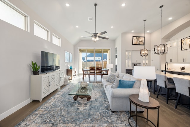 living room featuring ceiling fan with notable chandelier, dark hardwood / wood-style flooring, and high vaulted ceiling