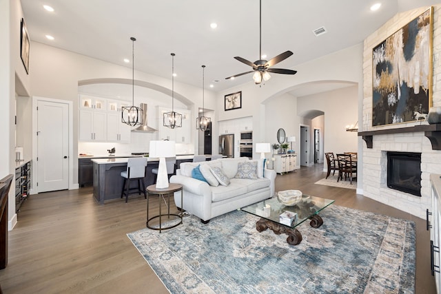 living room with ceiling fan, dark hardwood / wood-style flooring, and a brick fireplace