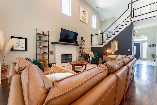 living room featuring a stone fireplace, dark hardwood / wood-style flooring, and high vaulted ceiling