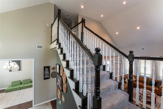 stairs with wood-type flooring, lofted ceiling, and an inviting chandelier