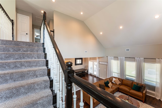 staircase with high vaulted ceiling and wood-type flooring