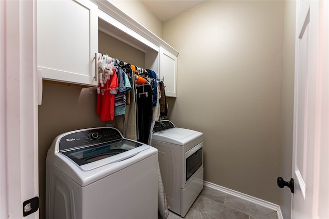 clothes washing area with light tile patterned flooring, washer and dryer, and cabinets