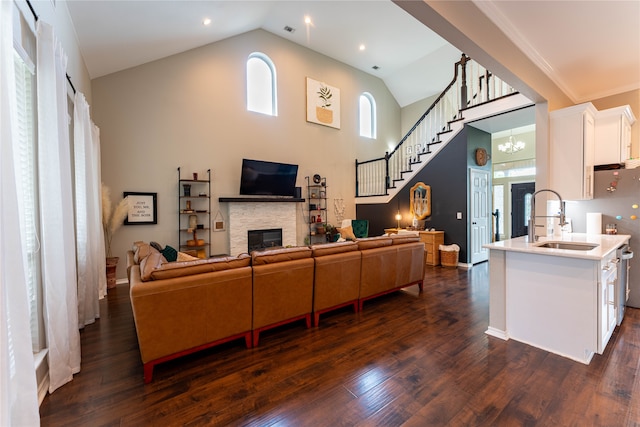 living room featuring a fireplace, dark hardwood / wood-style floors, sink, and high vaulted ceiling