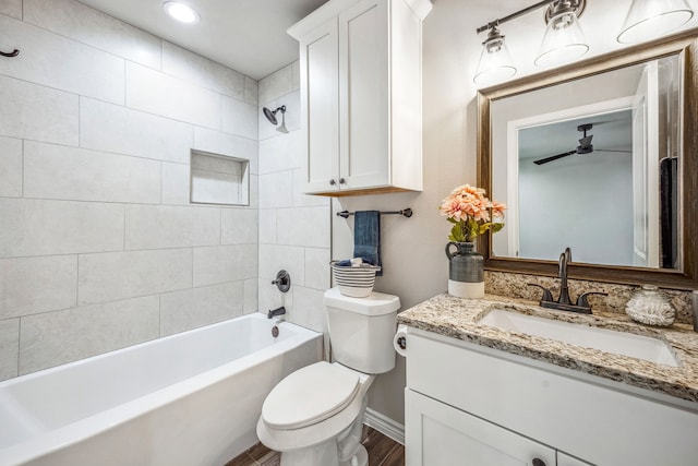 full bathroom with tiled shower / bath, vanity, hardwood / wood-style floors, and toilet