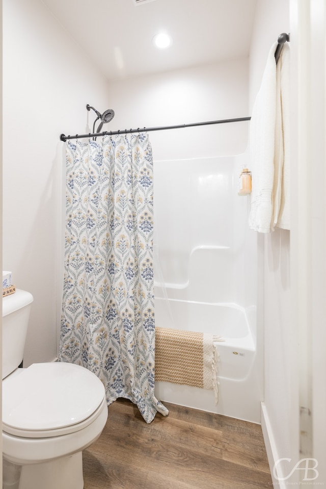 bathroom with wood-type flooring, shower / tub combo, and toilet