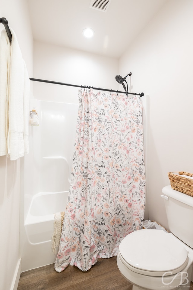 bathroom featuring wood-type flooring, shower / bathtub combination with curtain, and toilet