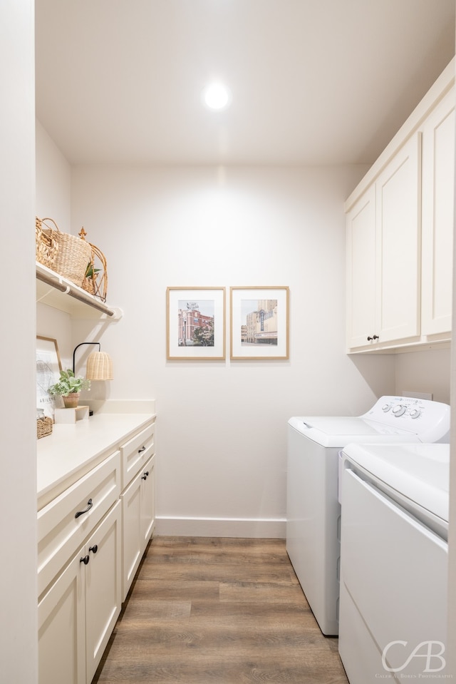 clothes washing area with cabinets, separate washer and dryer, and hardwood / wood-style flooring