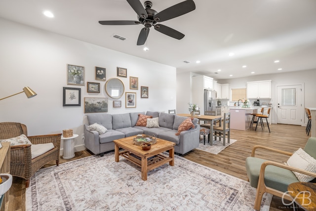 living room with ceiling fan, light hardwood / wood-style flooring, and sink