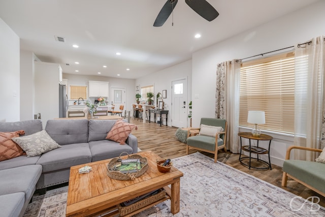 living room with light hardwood / wood-style floors, sink, and ceiling fan