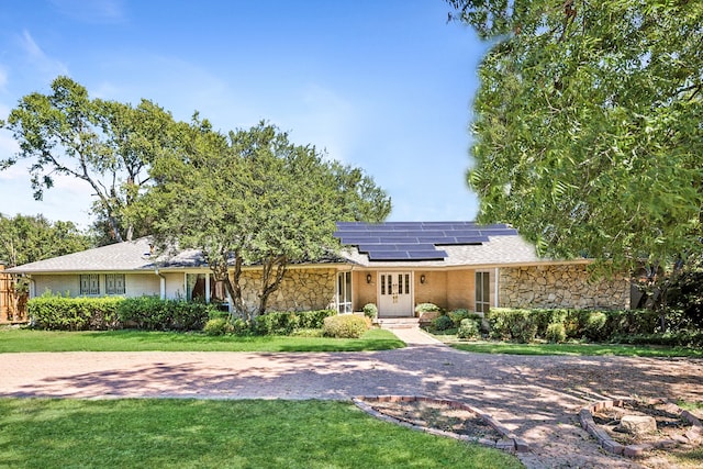 ranch-style home featuring a front lawn and solar panels