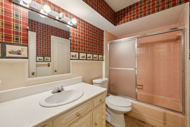 full bathroom featuring tile patterned floors, bath / shower combo with glass door, vanity, and toilet