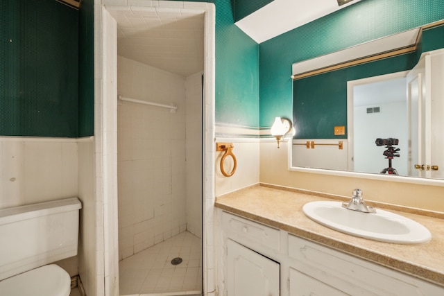 bathroom with a tile shower, vanity, and toilet