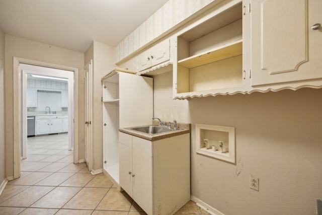 laundry area featuring light tile patterned floors, sink, washer hookup, and cabinets