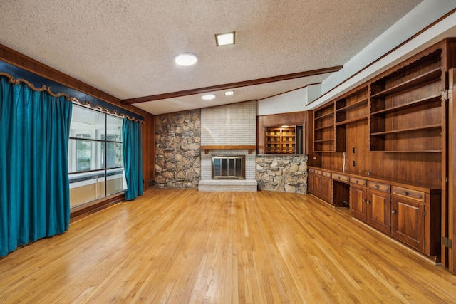 unfurnished living room with lofted ceiling with beams, light hardwood / wood-style floors, a textured ceiling, and a fireplace