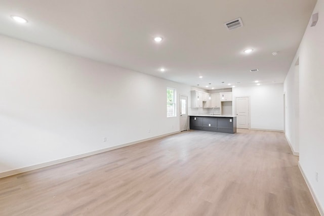 unfurnished living room featuring sink and light hardwood / wood-style flooring