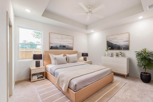 carpeted bedroom featuring ceiling fan and a tray ceiling