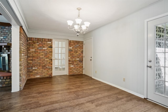 interior space featuring brick wall, crown molding, dark hardwood / wood-style flooring, and a chandelier