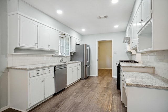 kitchen with light stone countertops, white cabinetry, hardwood / wood-style floors, and stainless steel appliances