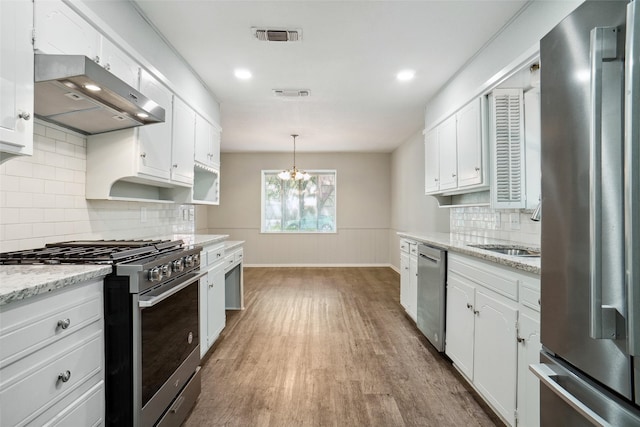 kitchen featuring appliances with stainless steel finishes, white cabinetry, dark wood-type flooring, and light stone counters