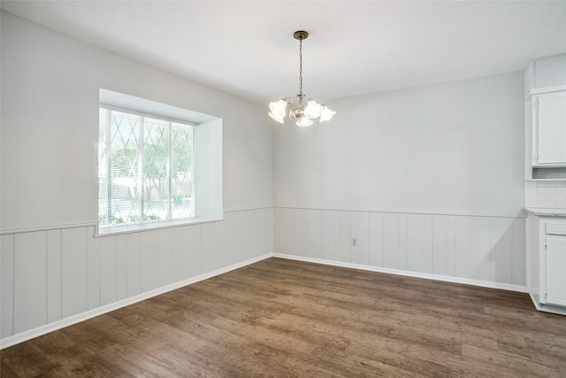 unfurnished dining area featuring an inviting chandelier and dark hardwood / wood-style flooring