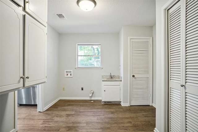 washroom featuring dark wood-type flooring, washer hookup, a textured ceiling, cabinets, and sink