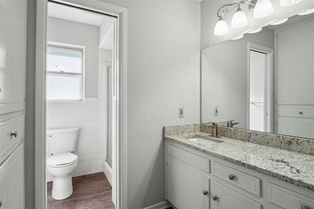 bathroom with vanity, wood-type flooring, walk in shower, tile walls, and toilet