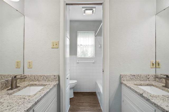 full bathroom featuring wood-type flooring, vanity, tile walls, and toilet