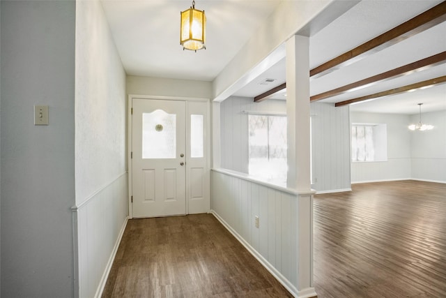 foyer entrance featuring a notable chandelier, beam ceiling, dark hardwood / wood-style floors, and plenty of natural light