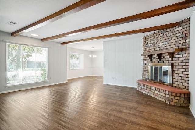 unfurnished living room with a brick fireplace, a chandelier, beamed ceiling, and dark hardwood / wood-style flooring