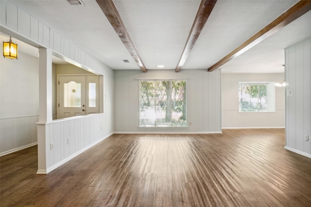 spare room featuring a textured ceiling, beam ceiling, dark hardwood / wood-style floors, and an inviting chandelier