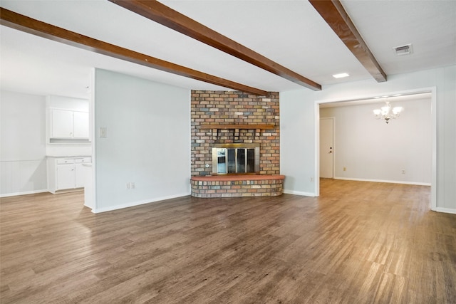 unfurnished living room featuring a brick fireplace, beamed ceiling, light wood-type flooring, and a chandelier