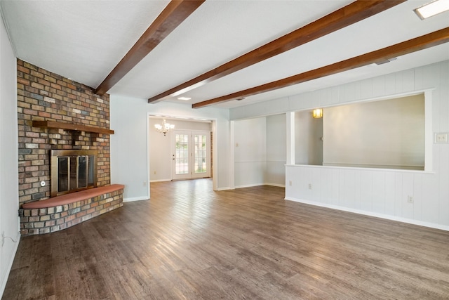 unfurnished living room with a fireplace, dark hardwood / wood-style flooring, beamed ceiling, french doors, and a notable chandelier