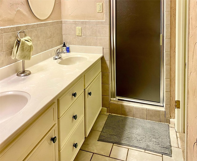 bathroom featuring tile patterned floors, a shower with door, vanity, and tile walls