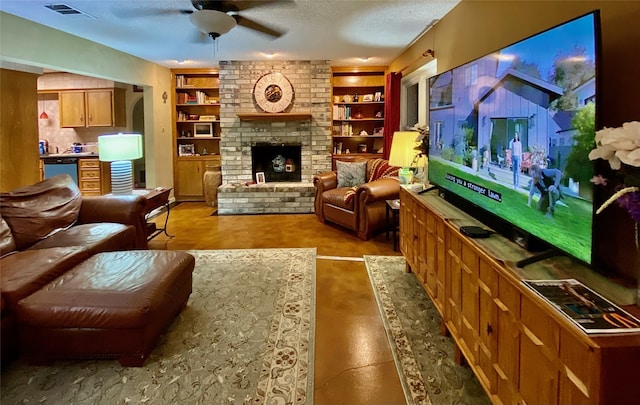 living room with a textured ceiling, built in shelves, ceiling fan, and a fireplace