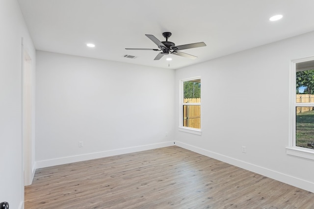 spare room featuring light hardwood / wood-style floors, ceiling fan, and plenty of natural light