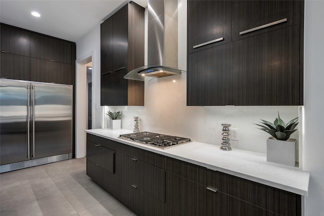 kitchen with appliances with stainless steel finishes, wall chimney exhaust hood, light tile patterned floors, and decorative backsplash