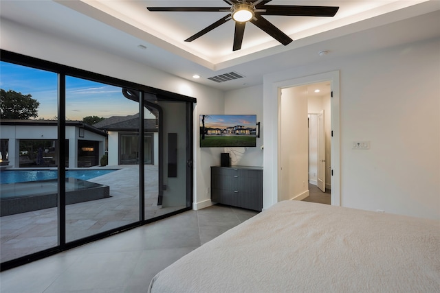 bedroom with ceiling fan, a raised ceiling, and access to exterior