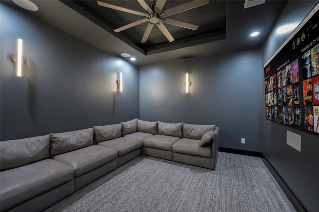 cinema room featuring carpet, ceiling fan, and a raised ceiling