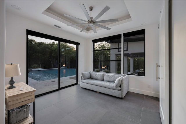 living room featuring ceiling fan and a tray ceiling