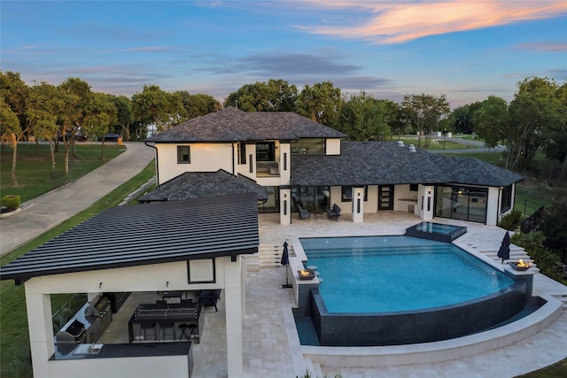 pool at dusk with exterior bar, an in ground hot tub, and a patio area