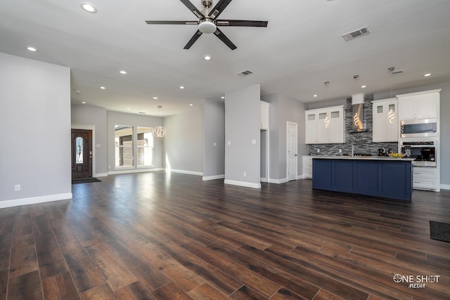 unfurnished living room featuring ceiling fan with notable chandelier, dark hardwood / wood-style floors, and sink