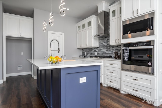 kitchen featuring built in microwave, tasteful backsplash, oven, an island with sink, and white cabinets