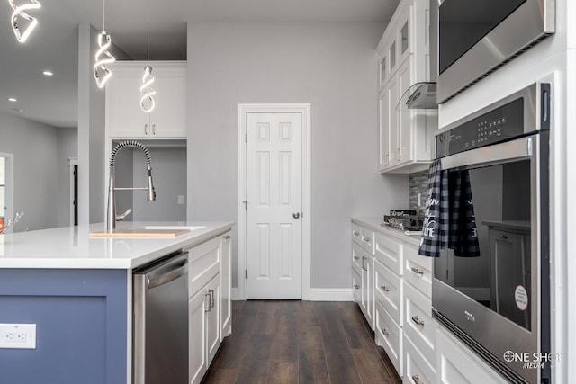 kitchen featuring white cabinetry, sink, hanging light fixtures, and appliances with stainless steel finishes