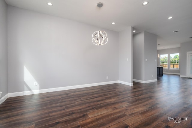 unfurnished room with a notable chandelier and dark hardwood / wood-style floors