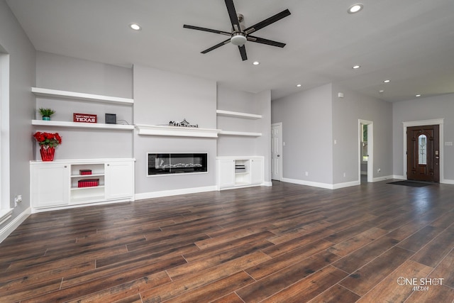 unfurnished living room featuring built in shelves and ceiling fan