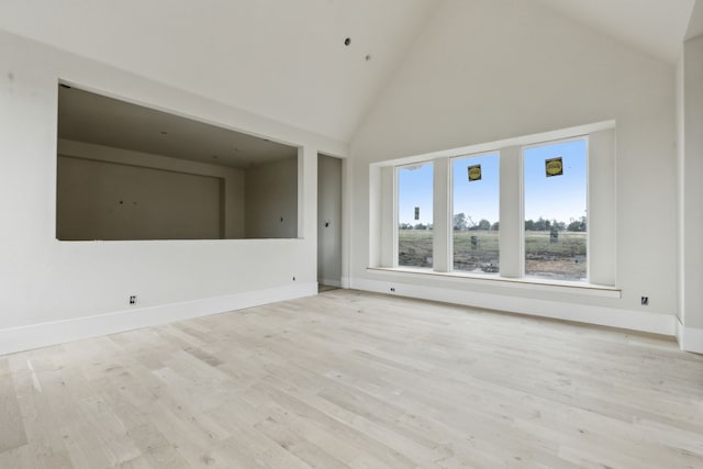 unfurnished living room featuring high vaulted ceiling and light hardwood / wood-style floors