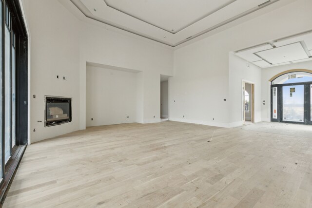 unfurnished living room featuring a towering ceiling and light hardwood / wood-style flooring